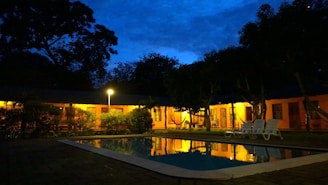 Evening shot of a pool enclosure glowing softly with interior lights behind a newly installed screen.