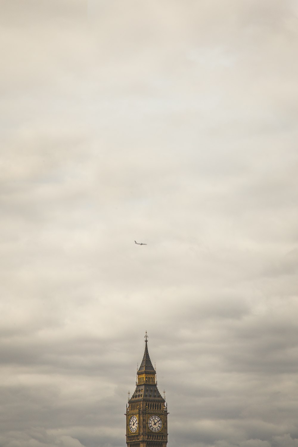 Elizabeth Tower under of white airliner during heavy clouds