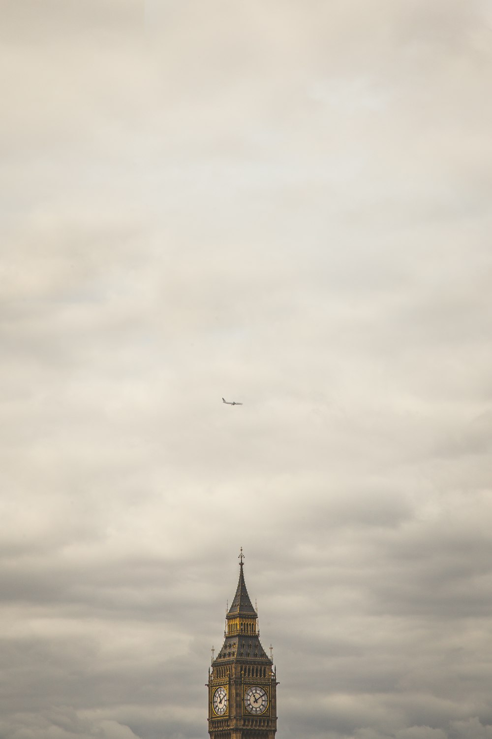 エリザベスタワー 厚い雲の間の白い旅客機の下