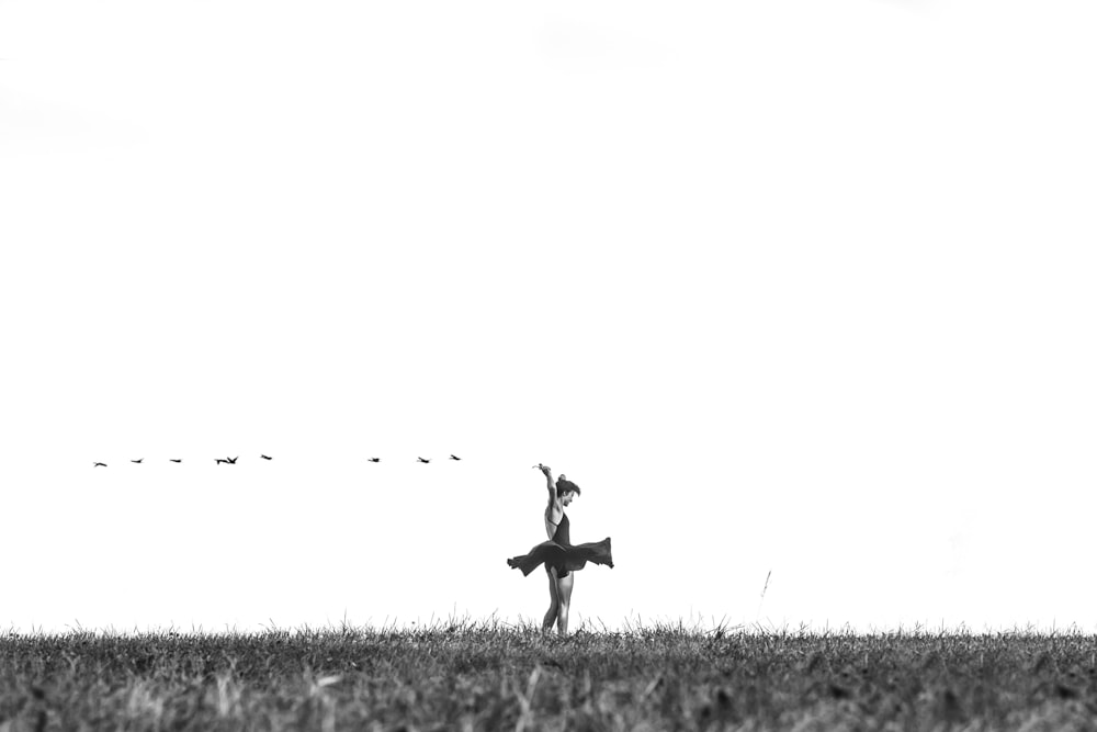greyscale photo of woman standing on grass field