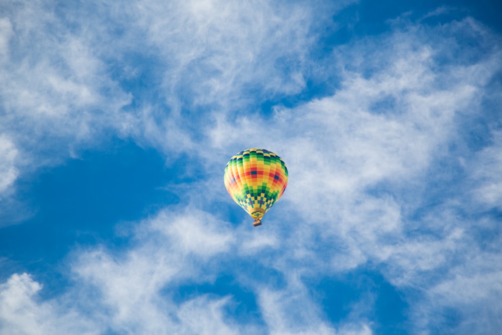 globo aerostático amarillo, verde y negro en el cielo