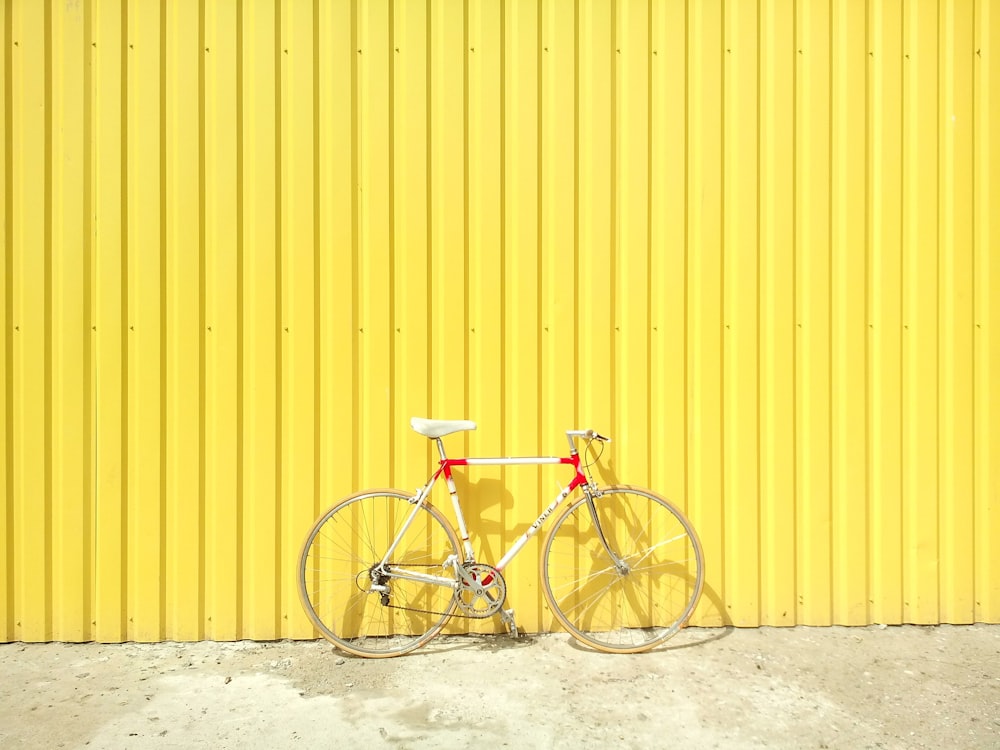 bicicleta hardtail branca e vermelha na parede amarela