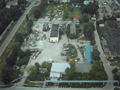 Aerial view of an industrial land plot ready for factory construction surrounded by green fields.