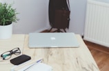 A sleek laptop placed on a wooden desk surrounded by stationery.