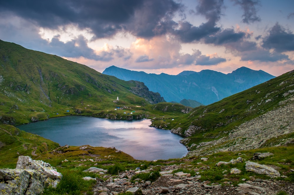 cuerpo de agua cerca de la montaña bajo las nubes