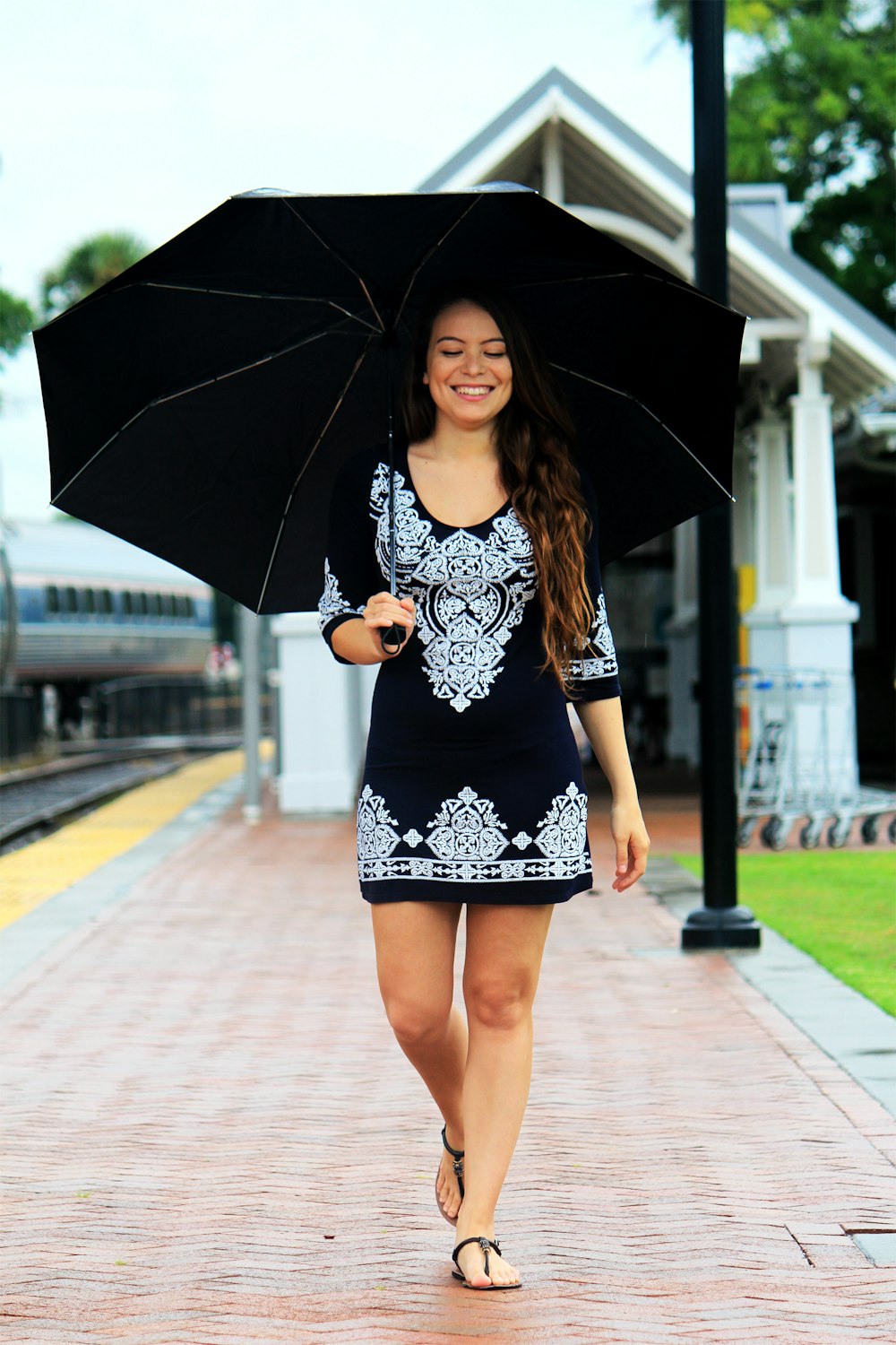 woman walking on brown pathway while holding black umbrella