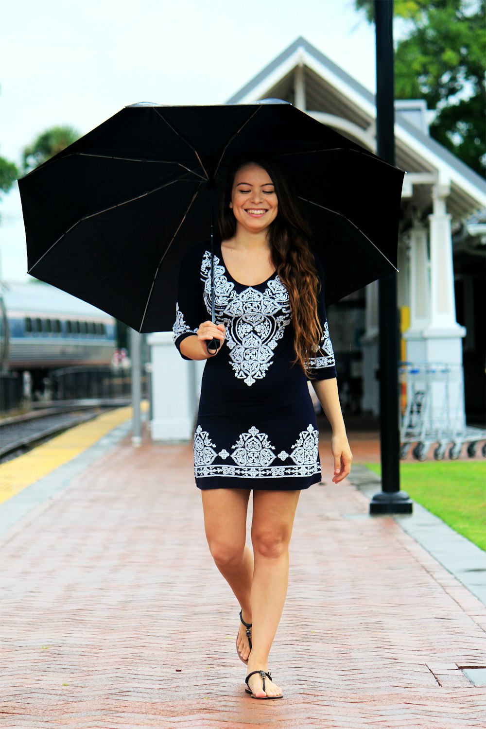 검은 우산을 들고 갈색 통로를 걷는 여자