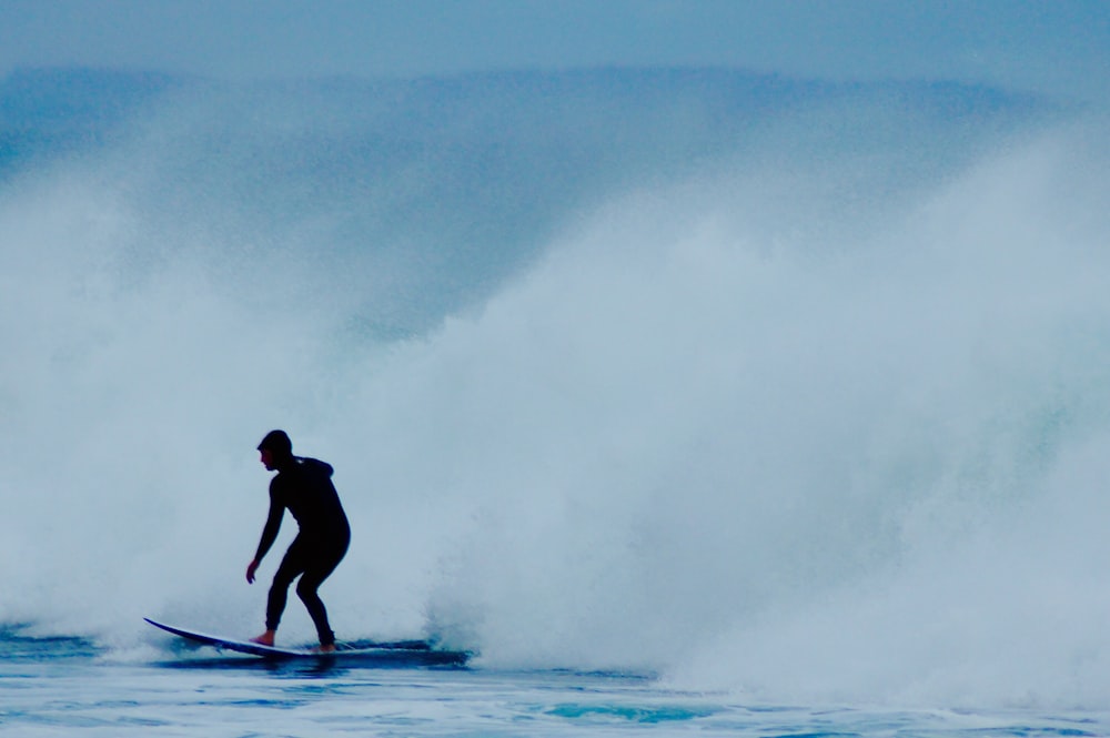 man riding surfboard near wave
