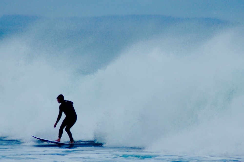 uomo che cavalca la tavola da surf vicino all'onda