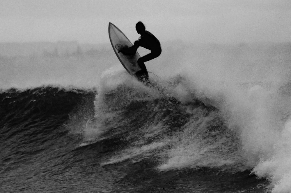Foto in scala di grigi di un uomo che fa surf