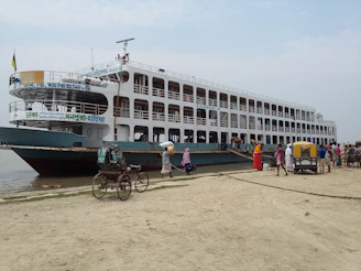 A ferry docked at a bustling port with travelers boarding and luggage being loaded.