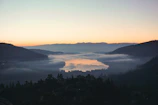 A serene sunrise over a misty Patagonian lake surrounded by towering mountains.