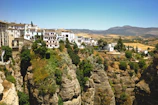 A drone shot capturing the whitewashed village of Mijas nestled among green hills under a bright blue sky.