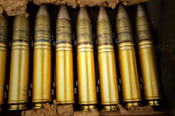 A team inspecting artillery shells in a clean, spacious workshop.