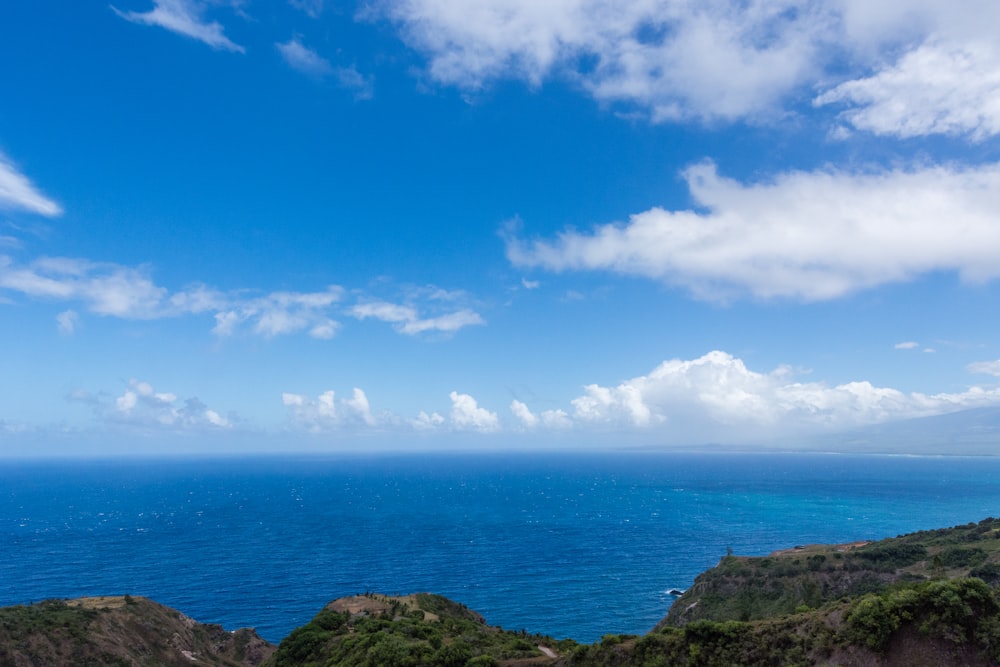 nubes azules sobre el océano cerca de la fotografía panorámica de la montaña