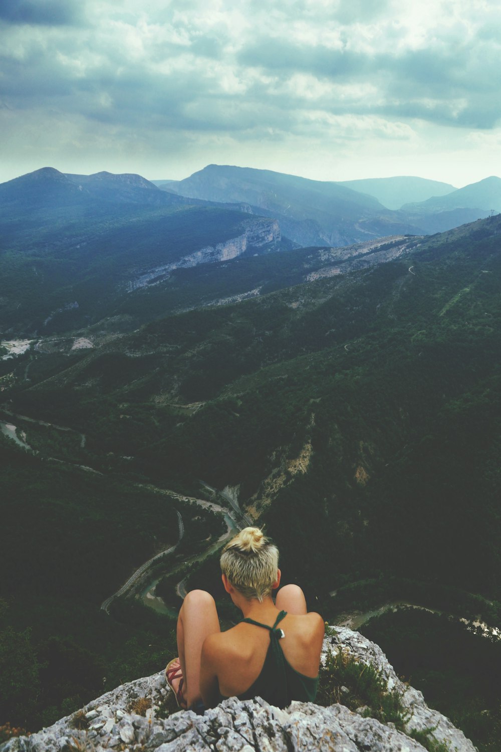 woman sitting next to cliff during daytime