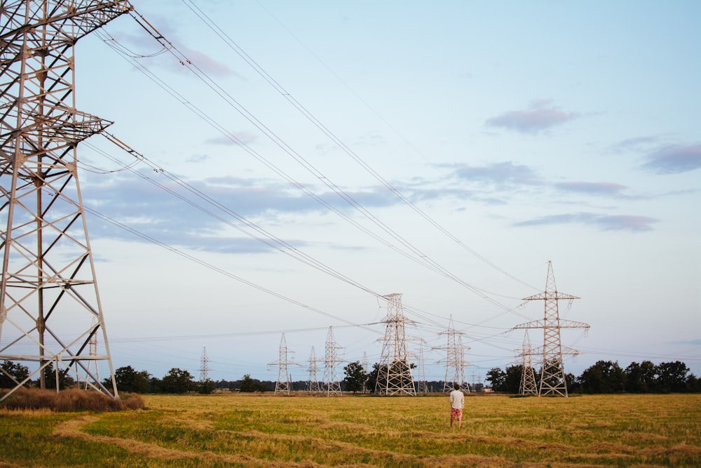 man standing on grass field facing on utility post