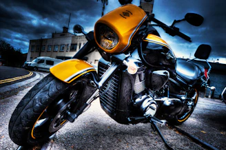 A sleek matte black motorcycle with vibrant yellow accents parked on a city street at sunset.