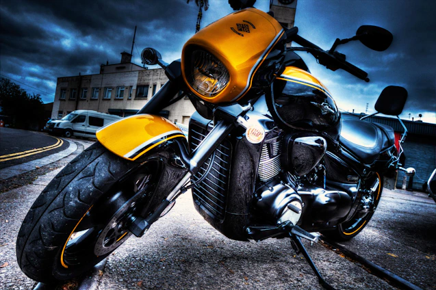 A sleek matte black motorcycle with vibrant yellow accents parked on a city street at sunset.