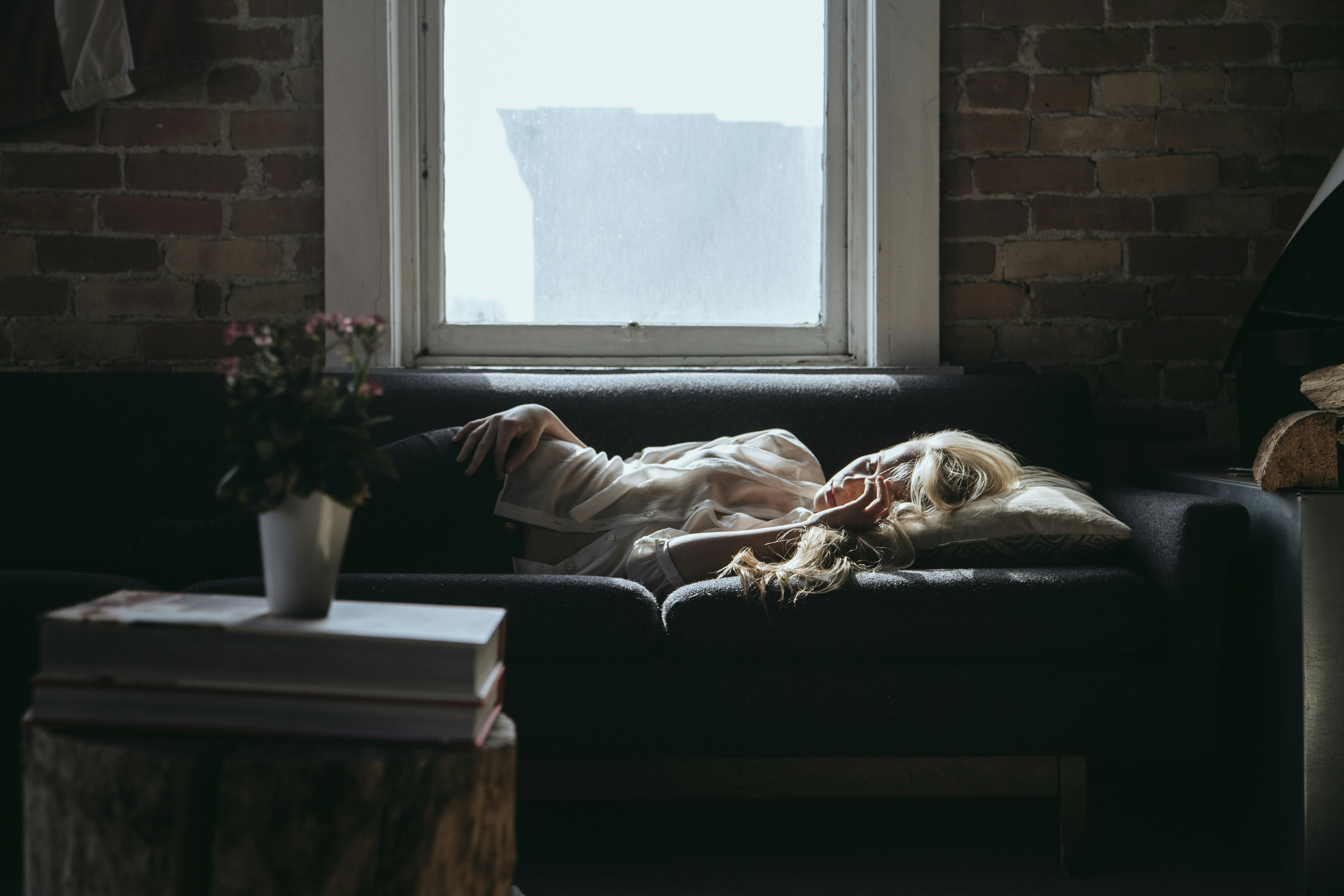 woman lying on sofa near closed window during daytime