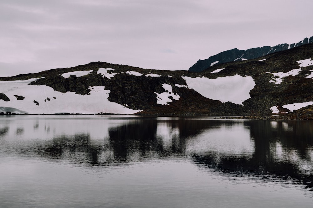 Specchio d'acqua vicino a montagna piena di neve