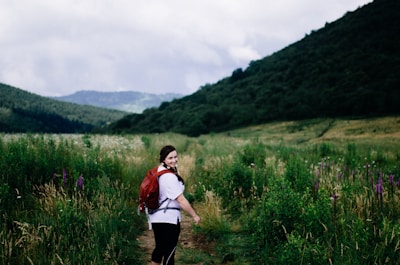 A travel influencer exploring a scenic mountain trail with a branded backpack.