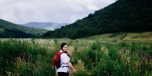 woman wearing red backpack surrounded plants