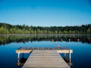 A wooden swimming dock reaching out into flat, still water