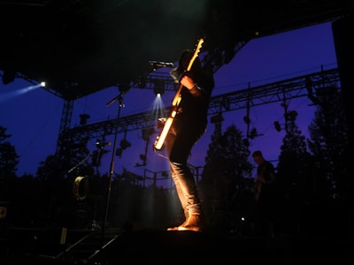 A musician playing guitar on a scenic outdoor stage.
