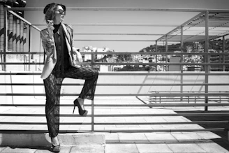 A stylish woman enjoying a sunny urban street, wearing a flowing Rokhani lawn outfit with subtle gold accents.
