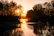 A serene sunset over the Nile with soft golden light reflecting on ancient temple ruins.
