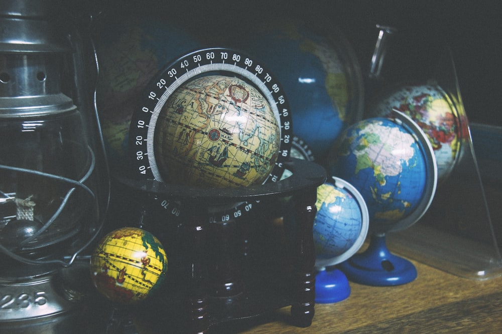 assorted mini desk globes on shelf near gray kerosene lantern