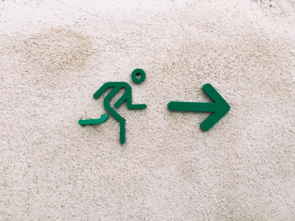 A green sign of a stick figure guy running towards a green arrow.