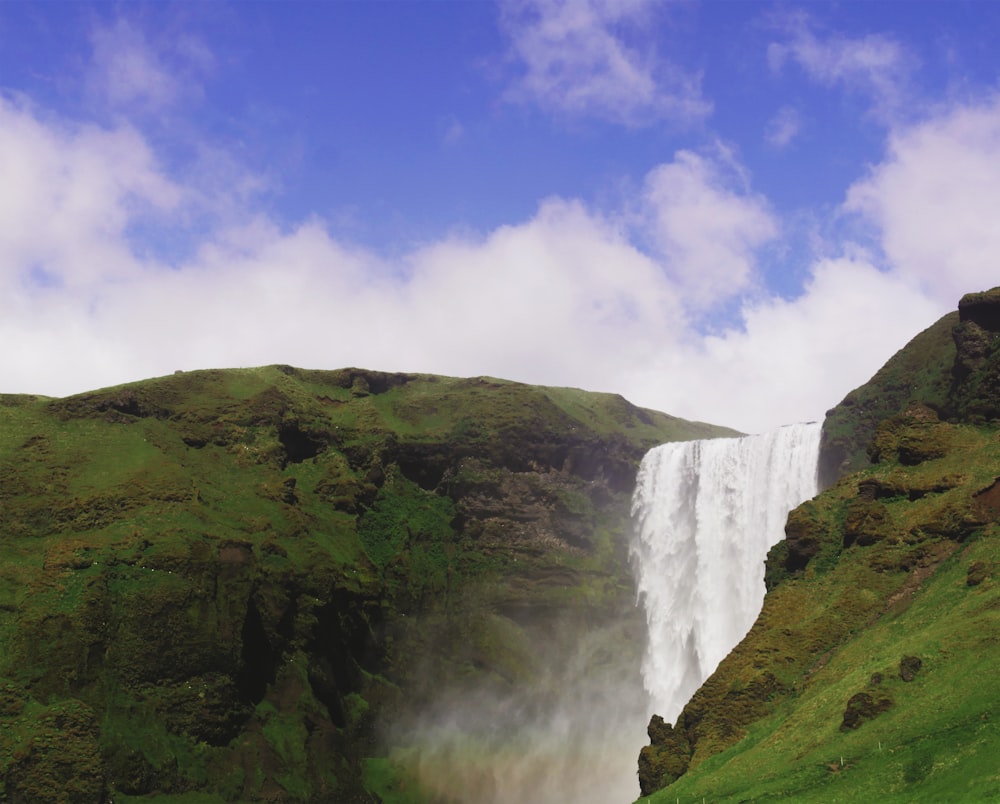 waterfalls between mountains under clear blue sky