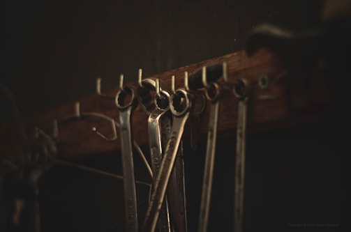Robust wrench and pliers resting on a metal surface with soft natural light.
