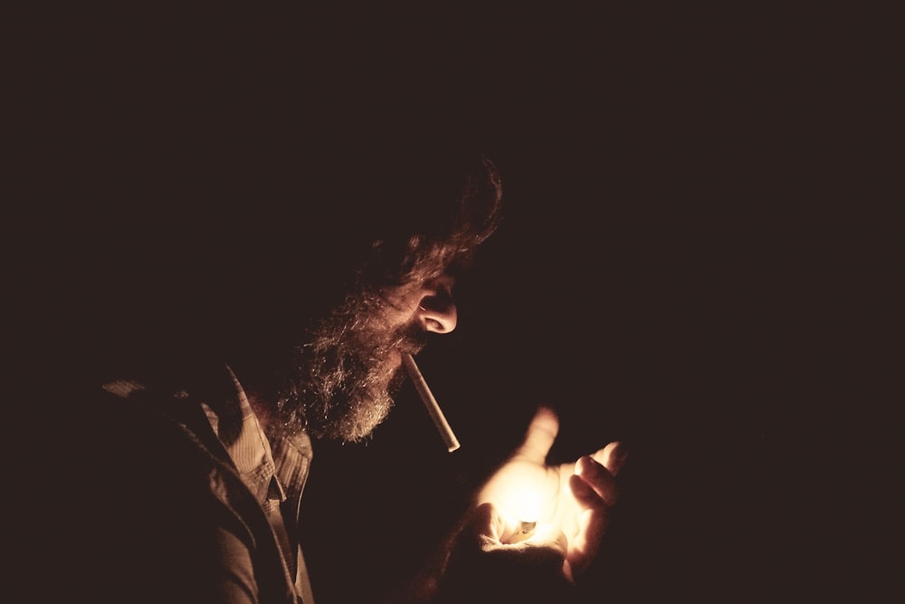 uomo con sigaretta sulla bocca che tiene accendino