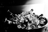 A collection of beer bottles immersed in ice within a large container. The scene is predominantly monochrome, providing a classic and timeless feel. The condensation and ice suggest a cold and refreshing atmosphere.