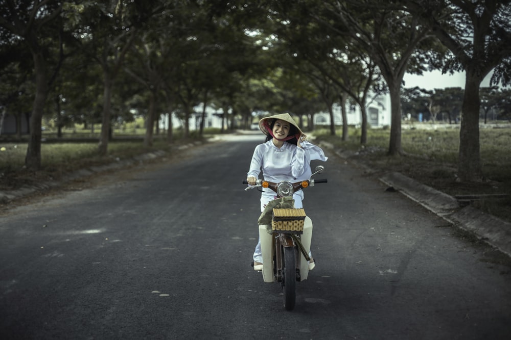 smiling woman riding scooter on road
