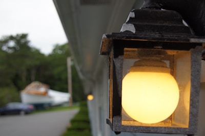 Close-up of a modern solar light fixture glowing brightly on a porch at dusk.