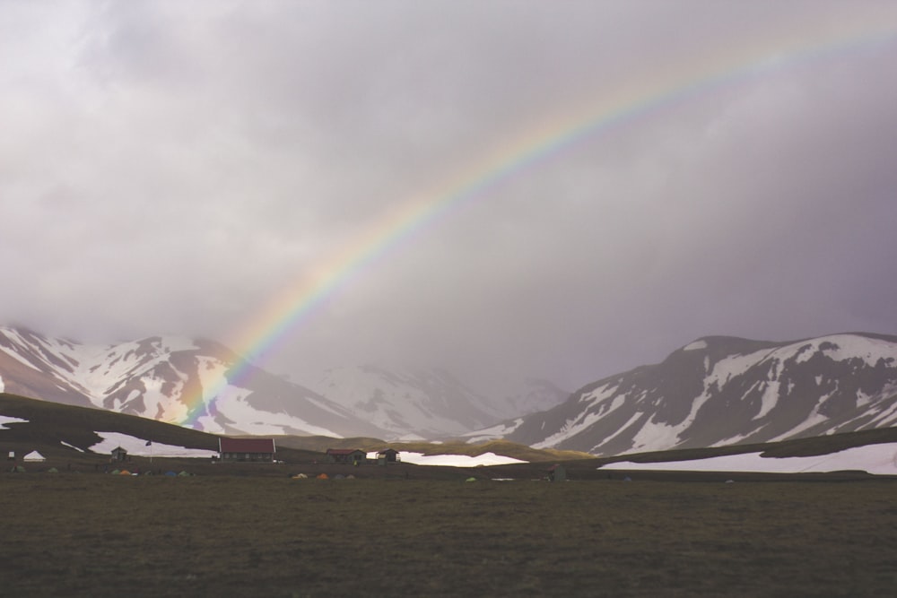 montagna grigia vicino allo specchio d'acqua sotto l'arcobaleno bianco