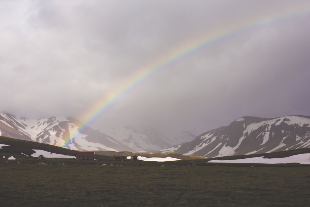 gray mountain near body of water under white rainbow