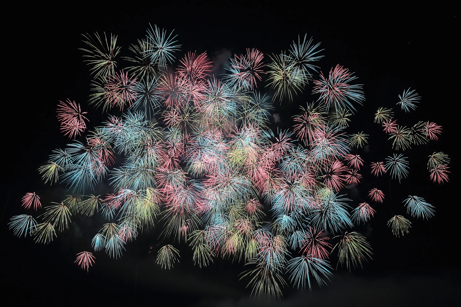 A shutter of a few seconds records a shell from burst to drooping trails, while f/8 to f/11 at ISO 100 stops the brightest cores burning out to white.