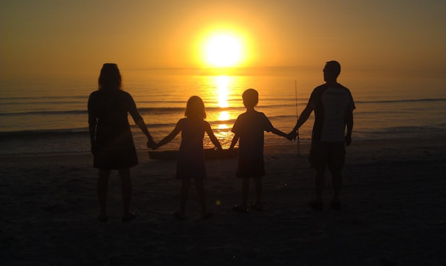 A warm, welcoming group of diverse people holding hands outdoors at sunset symbolizing unity and hope.