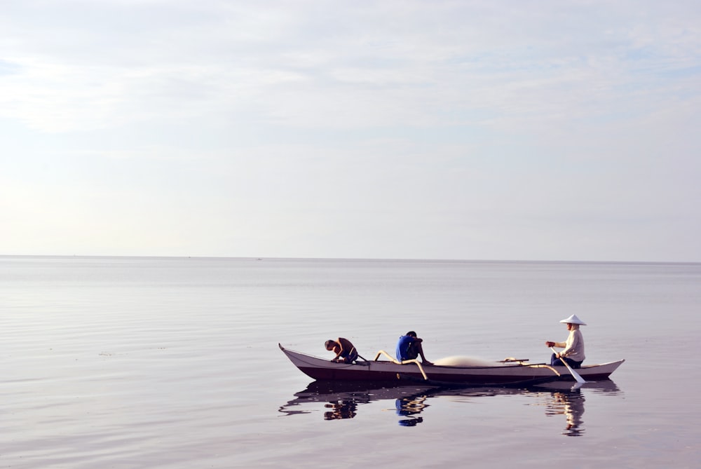 three person riding canoe at sea