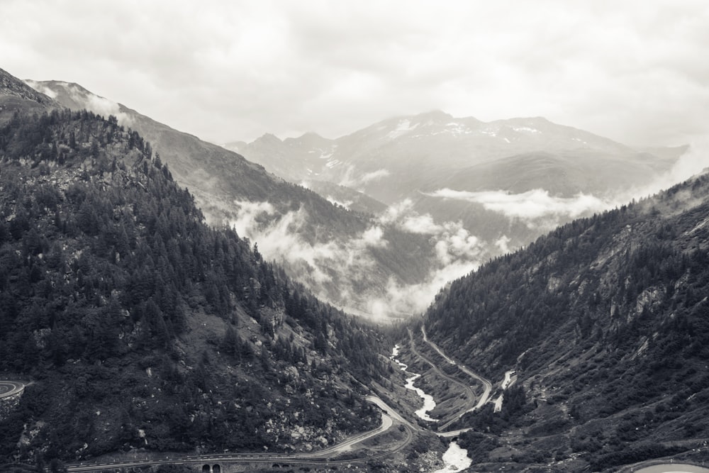 낮 동안 산에서 강과 도로의 회색조 사진