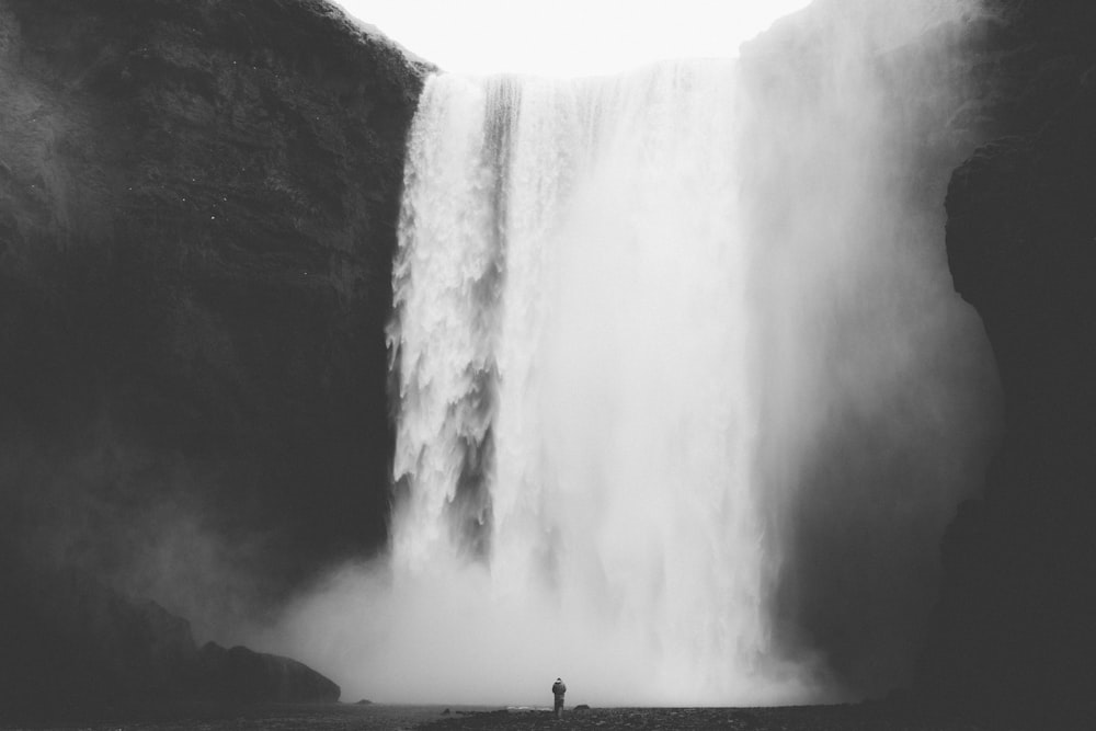 grayscale photo of man facing waterfalls