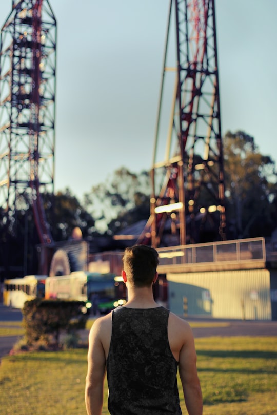 standing man wearing black tank top looking at towers in Dreamworld Australia