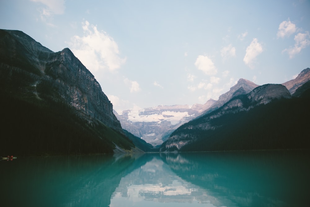 mountain range near body of water under blue skies