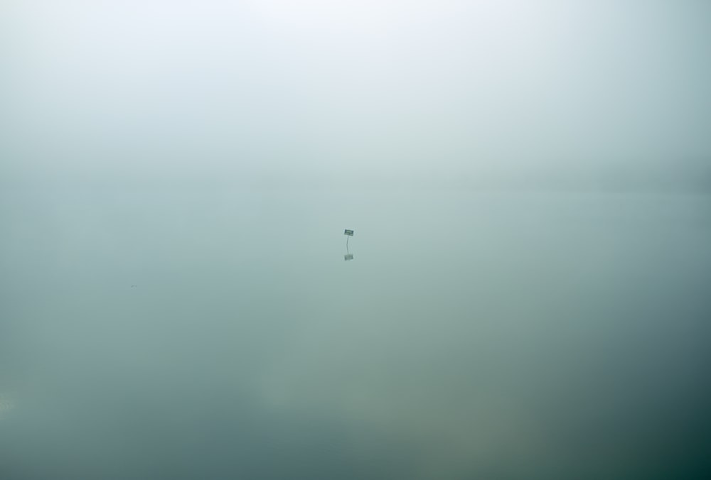 Single isolated sign sits in eerie still waters covered in clouds