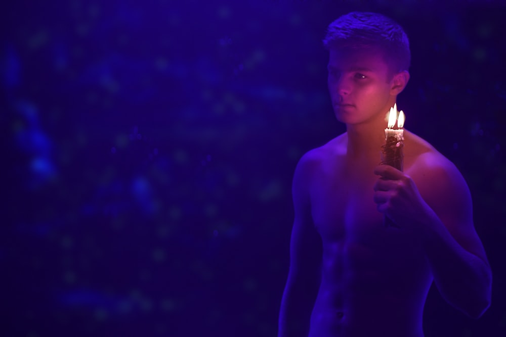 topless man holding lit candles